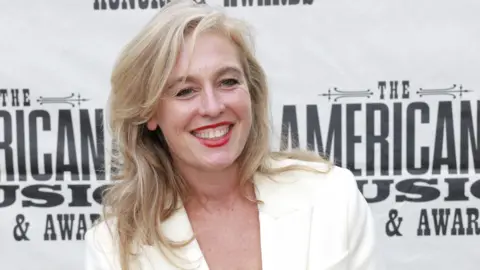 Why Spotify has no button to filter out AI music Getty Images Tift Merritt on the red carpet of an awards ceremony in Nashville, Tennessee. Smiling, with blonde hair, she wears a white jacket.