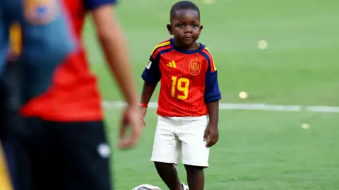 Reuters Spain's Lamine Yamal's brother Keyne plays football on the pitch after Spain won the World Cup