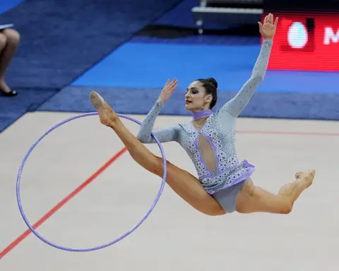 Ex-wife of Dubai ruler's nephew in custody, prosecutors say AFP via Getty Images Zeynab Javadli at a gymnastics competition in 2011. She is wearing a blue and purple leotard embellished with jewels. The photo captures her jumping in the air doing a split kick with her front leg and arm going through a large hoop.
