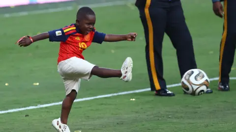Reuters Keyne smiles as he kicks a football on the pitch 