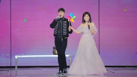 Visual China Group via Getty Images Zhang Jie and Xie Na holding hands as they perform on a stage