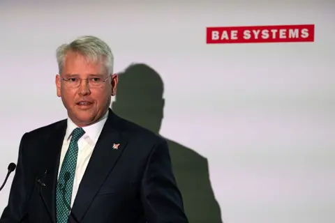 Getty Images Dr. Charles Woodburn, Group Chief Executive Officer of BAE Systems, speaks at the BAE Systems stand during the launch of the uncrewed Collaborative Combat Aircraft (CCA) named Brontanax on July 22, 2026 in Farnborough